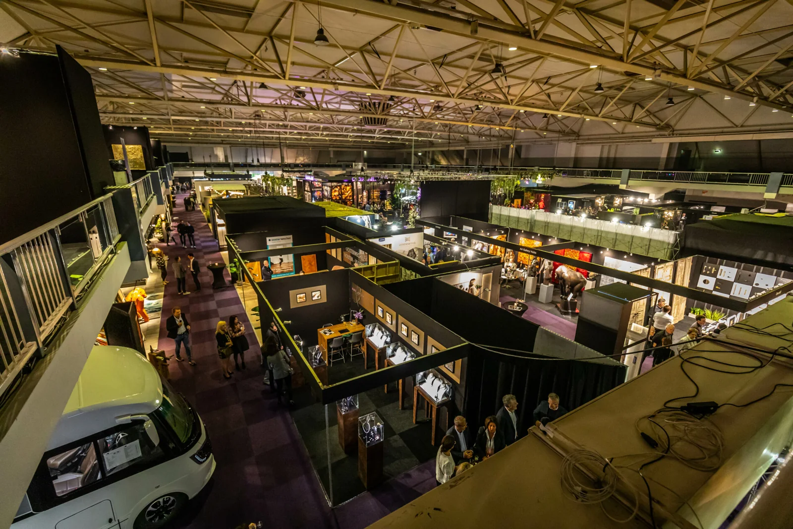 Een beursvloer met stands, verlichting en bezoekers